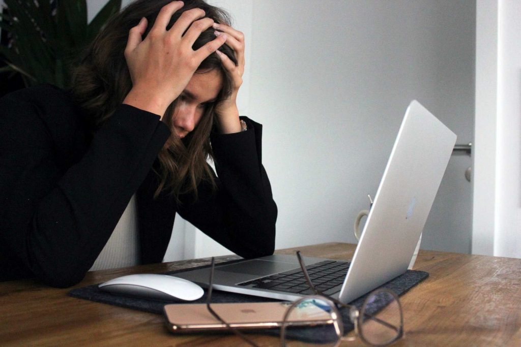 a woman holding her head. Frustrated with the website uptime and downtime.